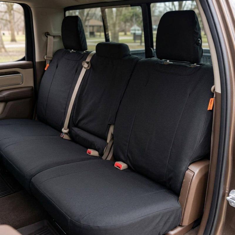 Ensemble de trois housses de siège noires TigerTough en Cordura pour Dodge Durango WD, installées sur la banquette arrière de l'habitacle d'un véhicule ; on voit ici la portière ouverte et le paysage extérieur à travers les vitres.
