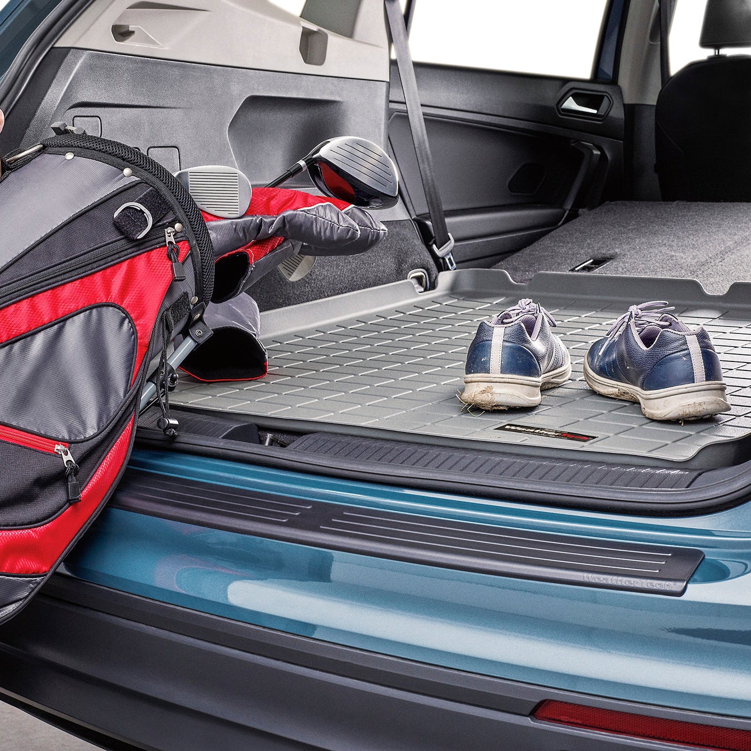 Une VW Tiguan équipée d'une protection de pare-chocs arrière protège un homme en train de charger un sac de golf dans le coffre arrière de la voiture